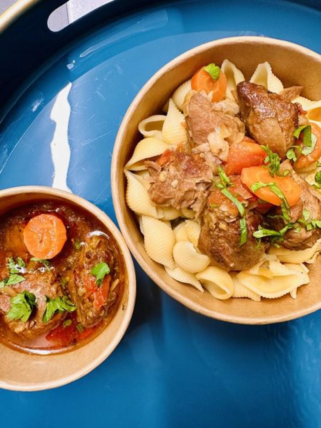 Un bol bleu de nouilles et de viande mijotée, servi avec des légumes