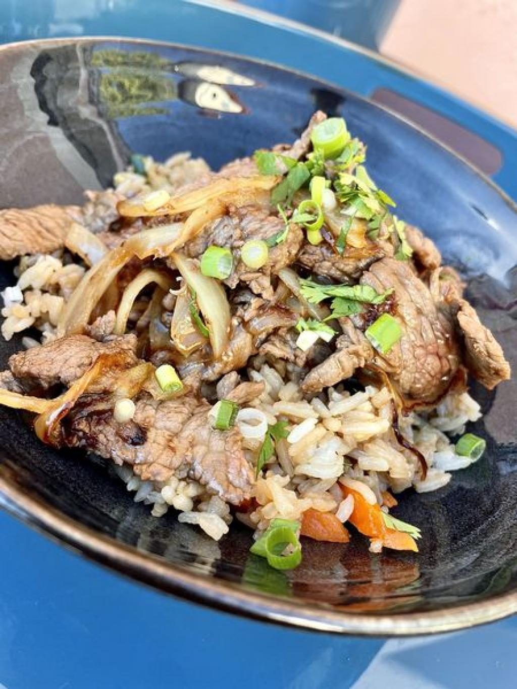Des nouilles sautées et de la viande effilochée dans une assiette creuse bleue