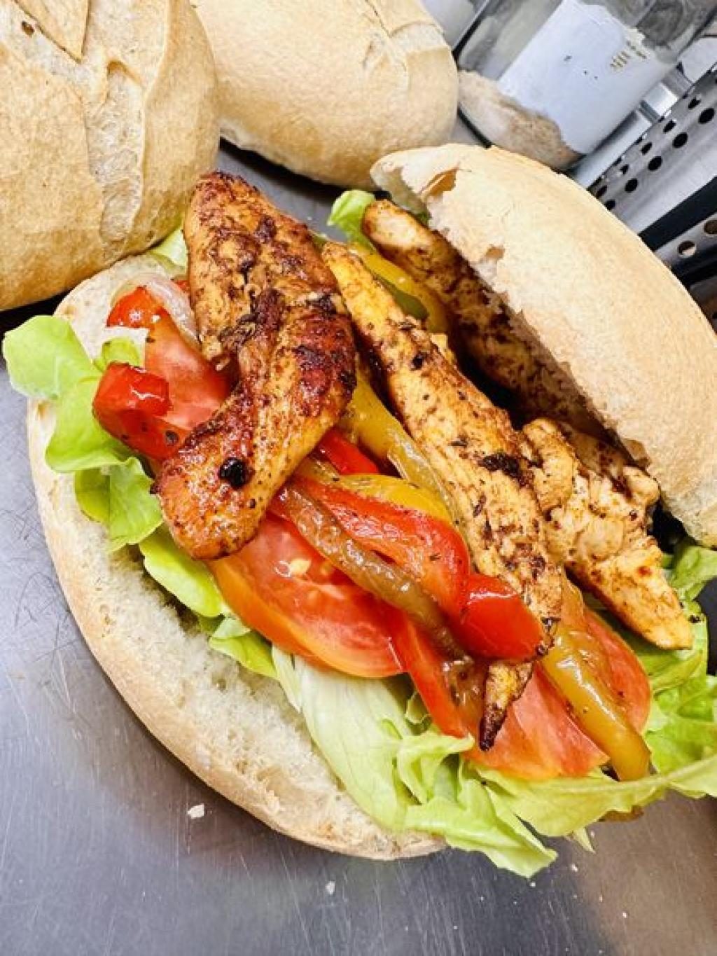 Un sandwich garni de poulet, tomates et salade