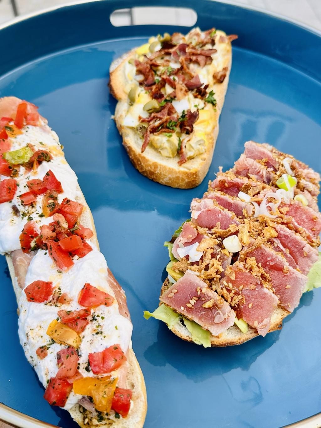 Deux tartines garnies de tomates et de thon mi-cuit, sur un plat bleu